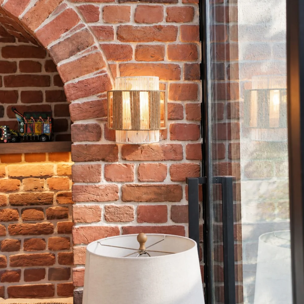 Woven rope wall light on brick beside the glass doors to the garden in a Sharjah Sustainable City villa