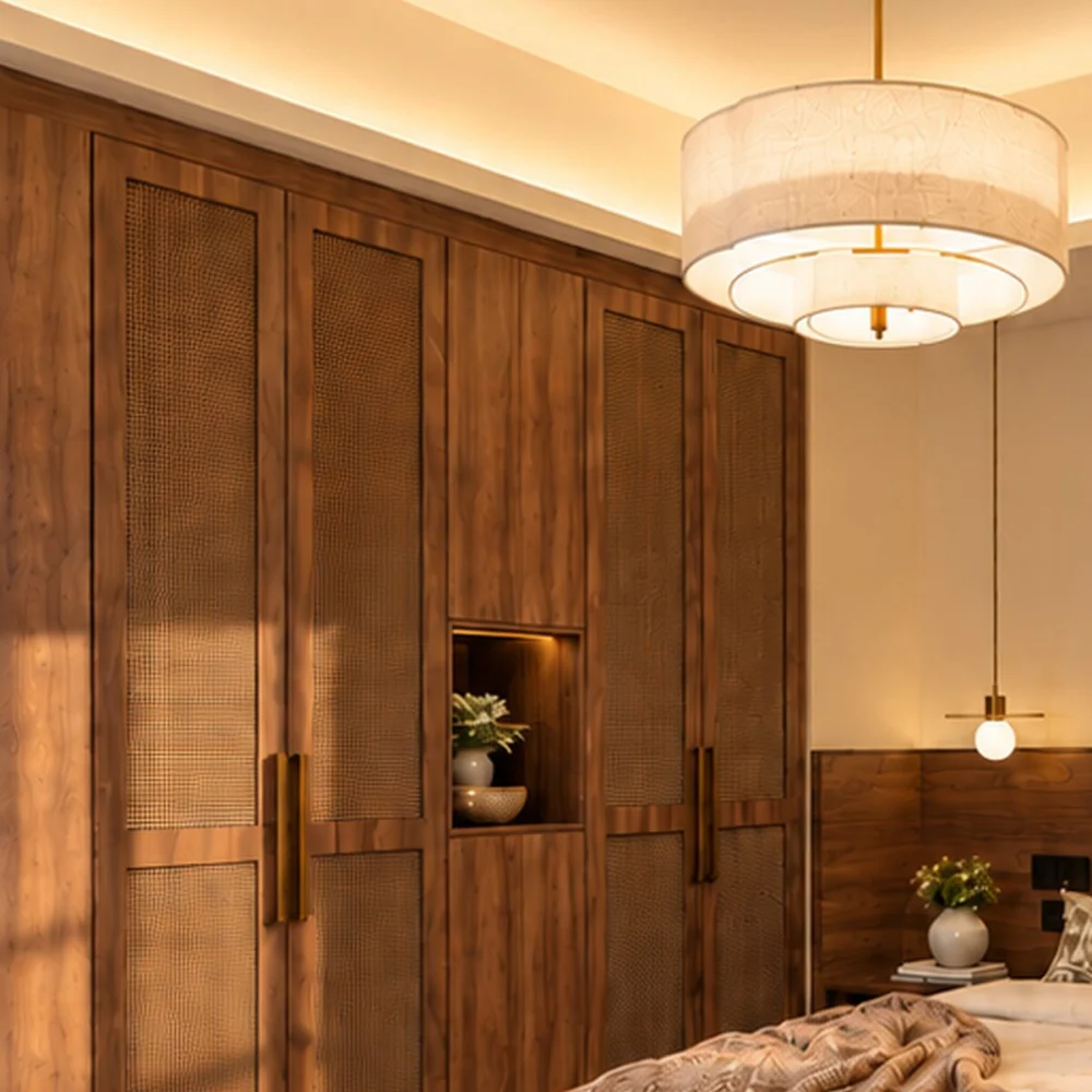 Full-height walnut wardrobes with rattan panels and a lit niche in the master bedroom of a Sharjah villa by Tohfa
